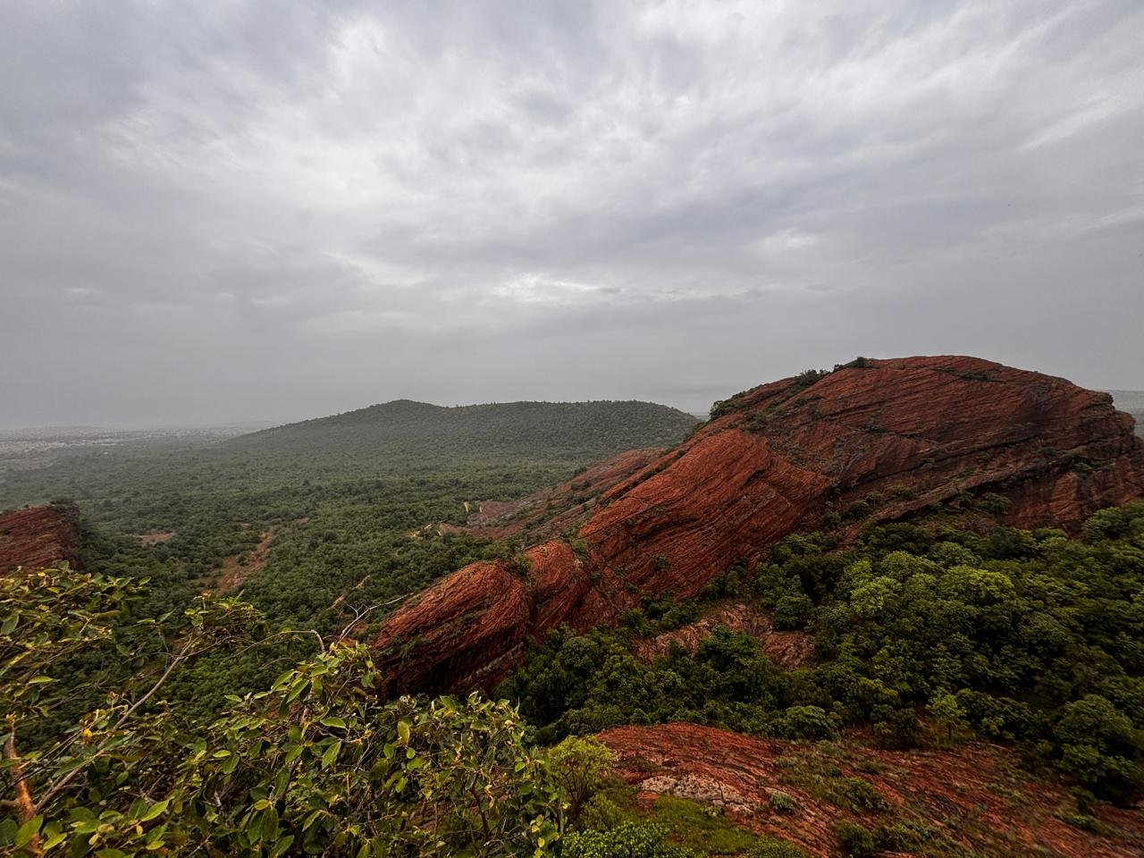 Red-rock ridge and green forest landscape of Mancherial